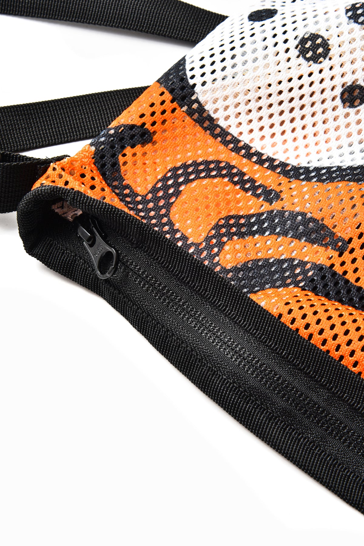 Close-up of a mesh bag or pouch with an orange and black patterned side, a white mesh top section with black dots, and a black zipper along the edge, shown on a white background.
