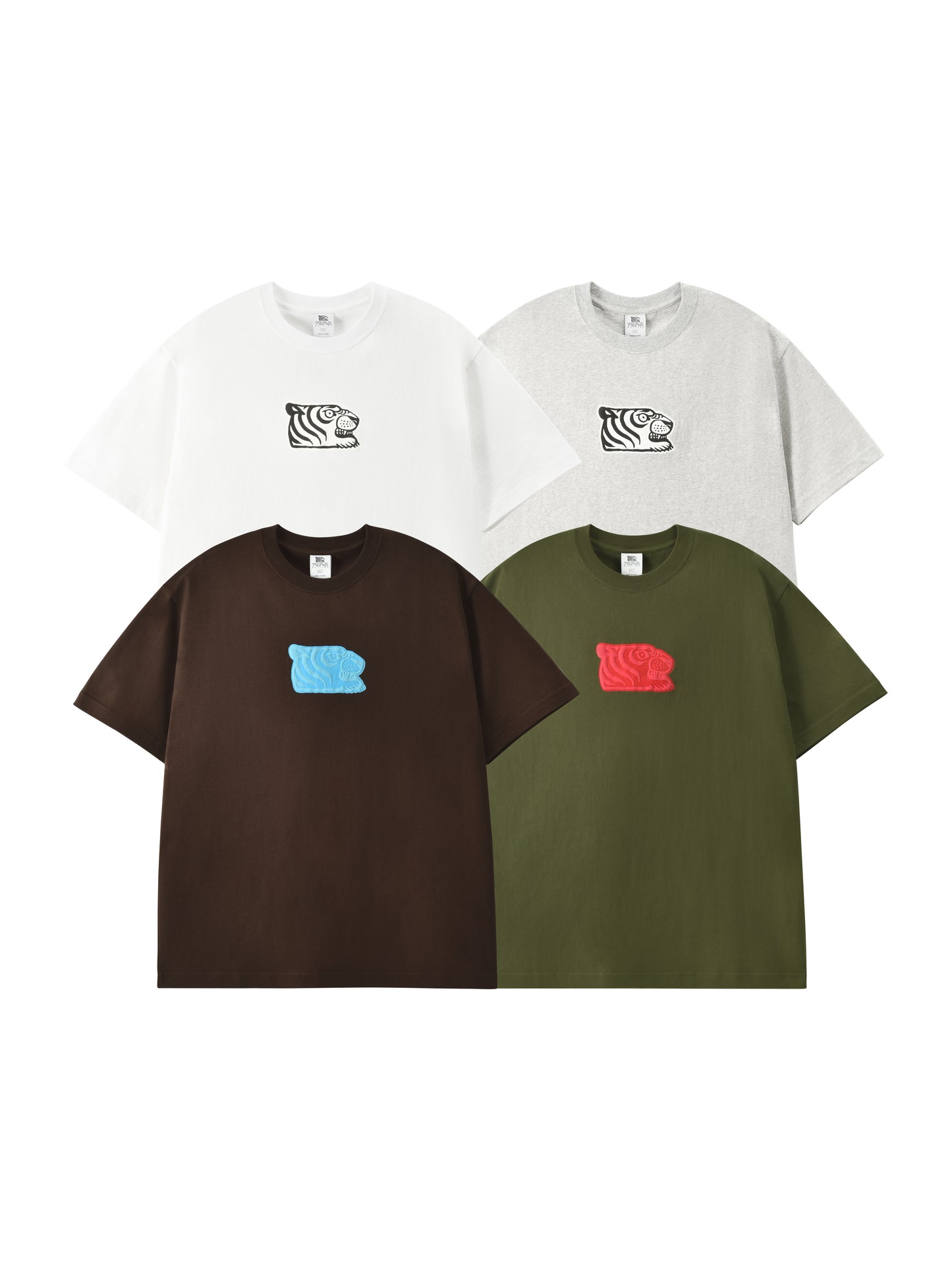 Four oversized short-sleeve T-shirts arranged in a 2x2 grid on a white background: white, light gray, dark brown, and olive green. Each shirt has a small embroidered tiger head chest graphic in a different color (black, white, light blue, and red).