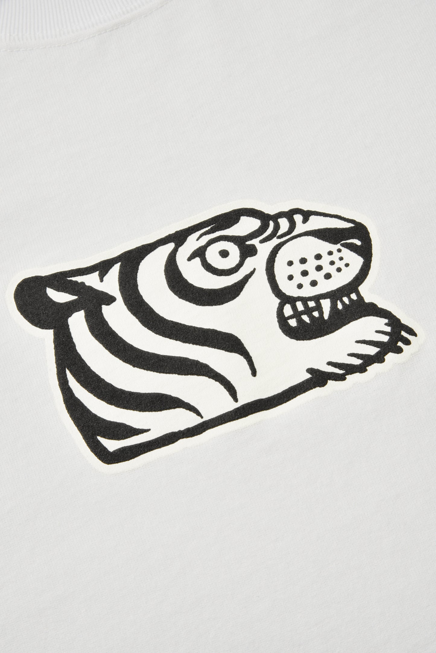 A close-up of a white fabric surface featuring a bold black graphic print of a stylized tiger head.
