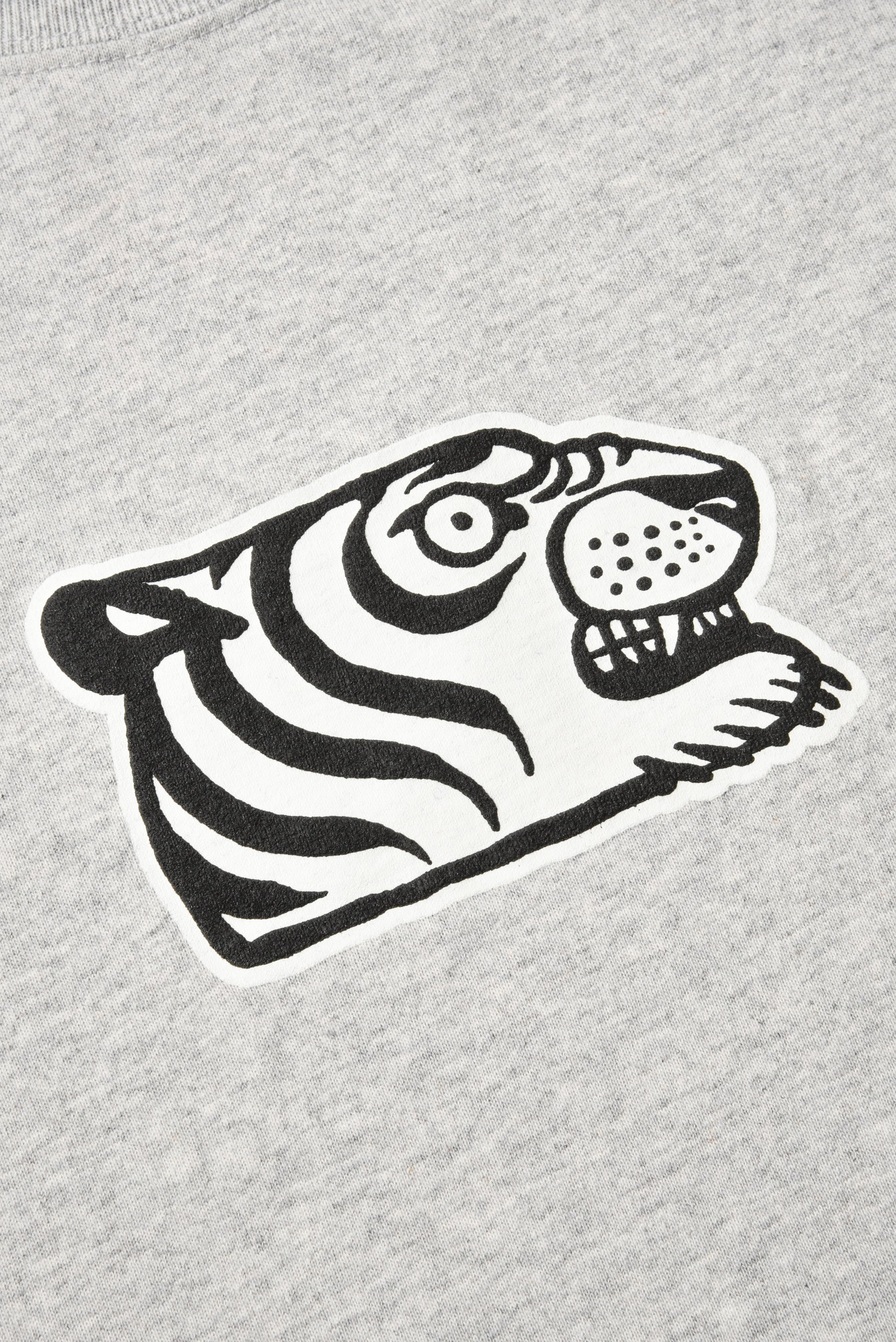 Close-up of a light heather gray sweatshirt featuring a stylized black and white tiger face graphic on the chest.