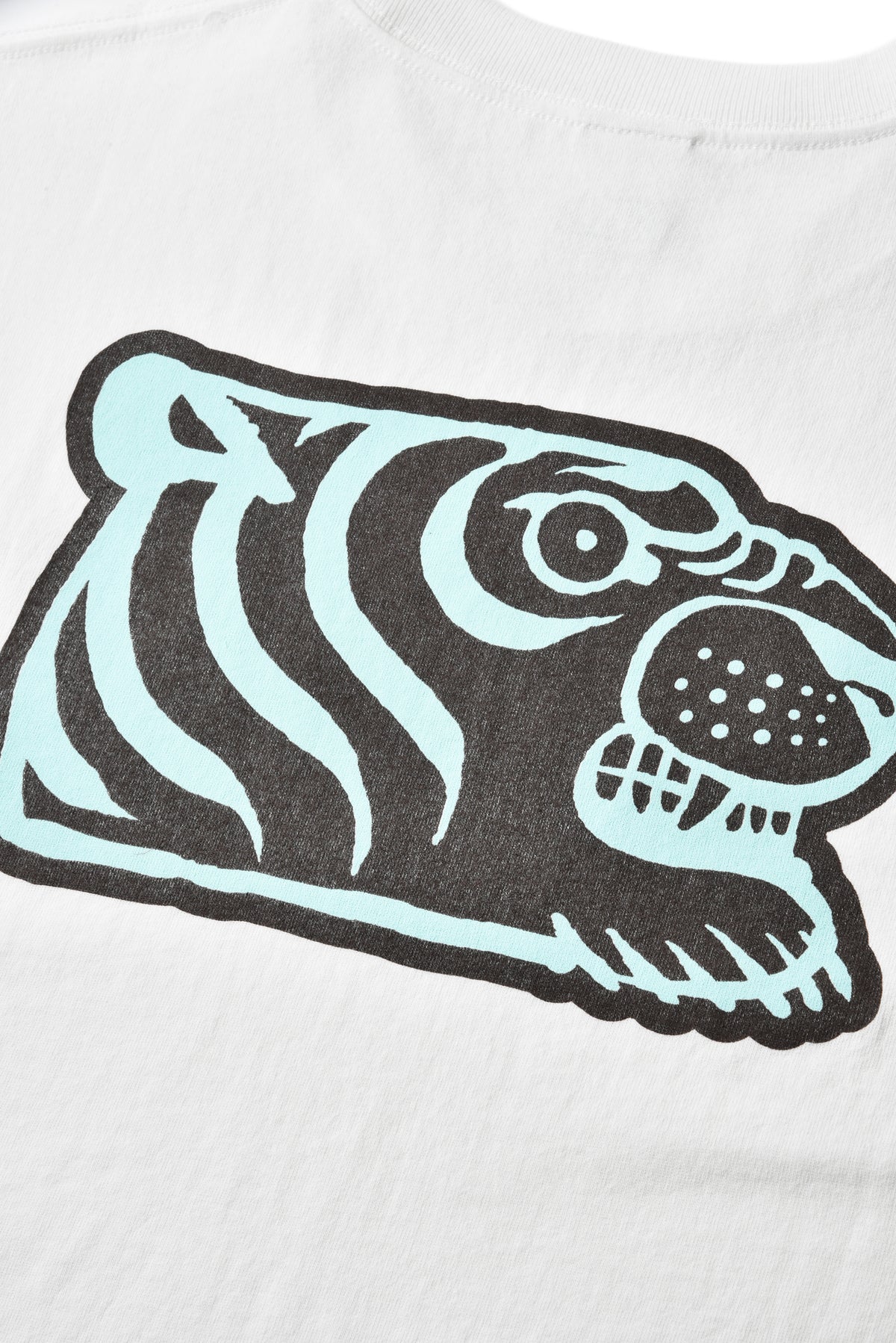Close-up of a white T-shirt featuring a stylized soulgoods tiger head graphic in black and pale mint blue.