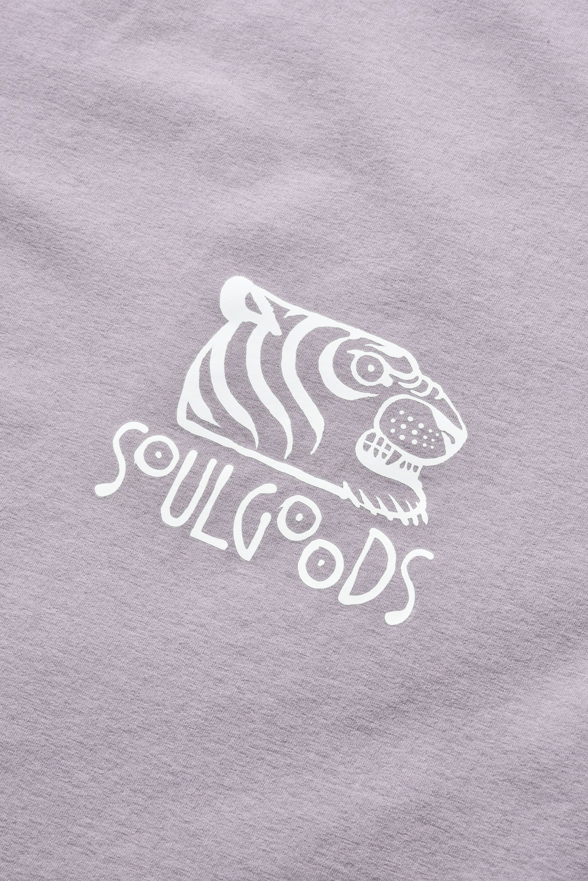 A close-up of a light lavender-purple t-shirt featuring a white screen-printed graphic of a tiger head above the text 'SOULGOODS'.