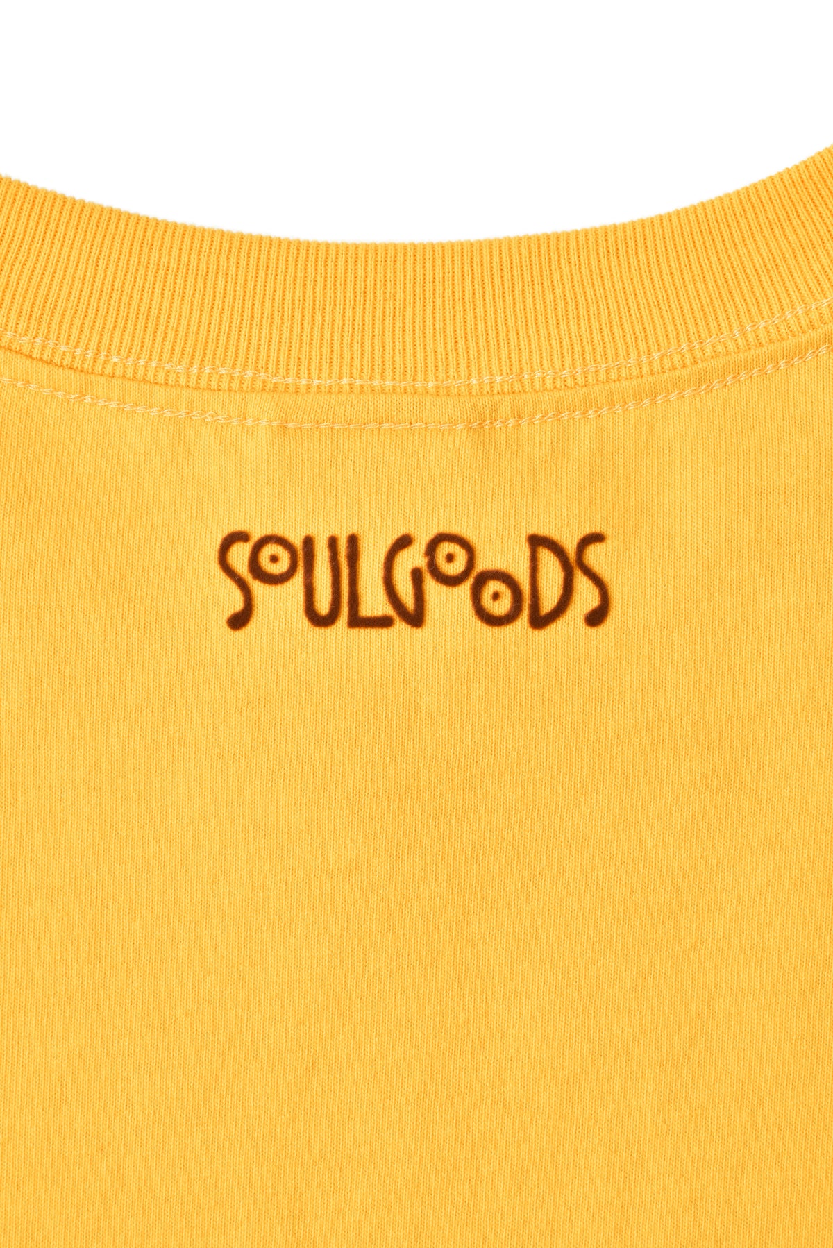 Close-up of a mustard yellow garment with 'SOULGOODS' branding.