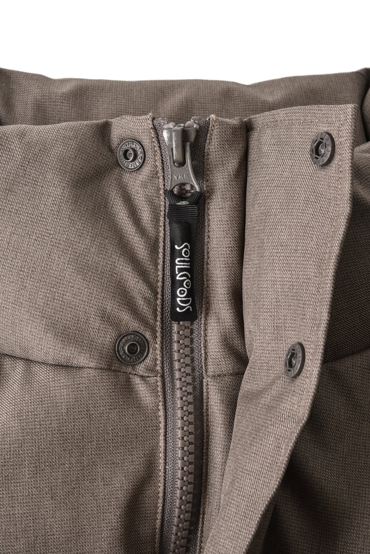 Close-up of a brown jacket with a zipper and visible brand logo.