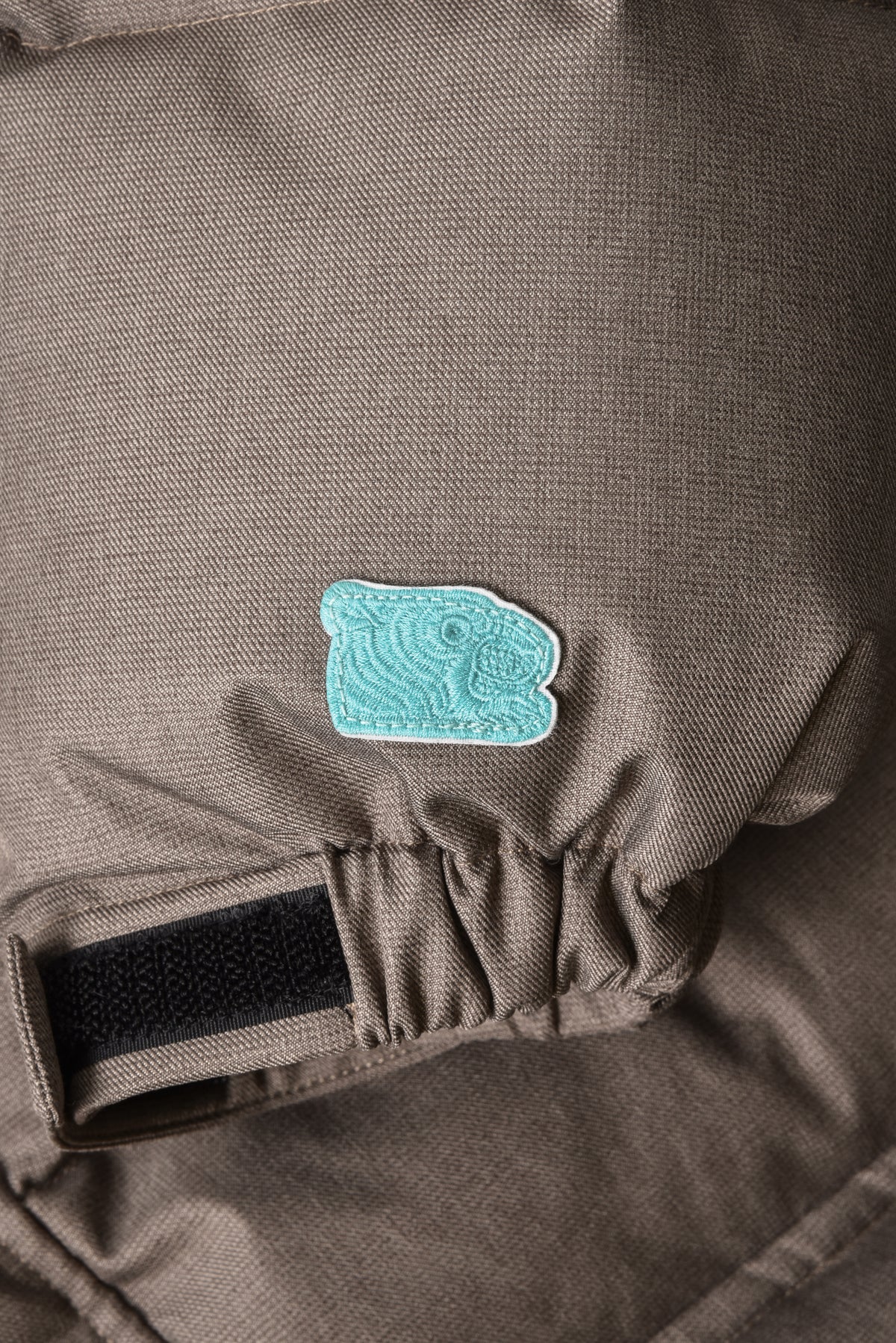 Close-up of a brown bag with a turquoise patch on a dark background