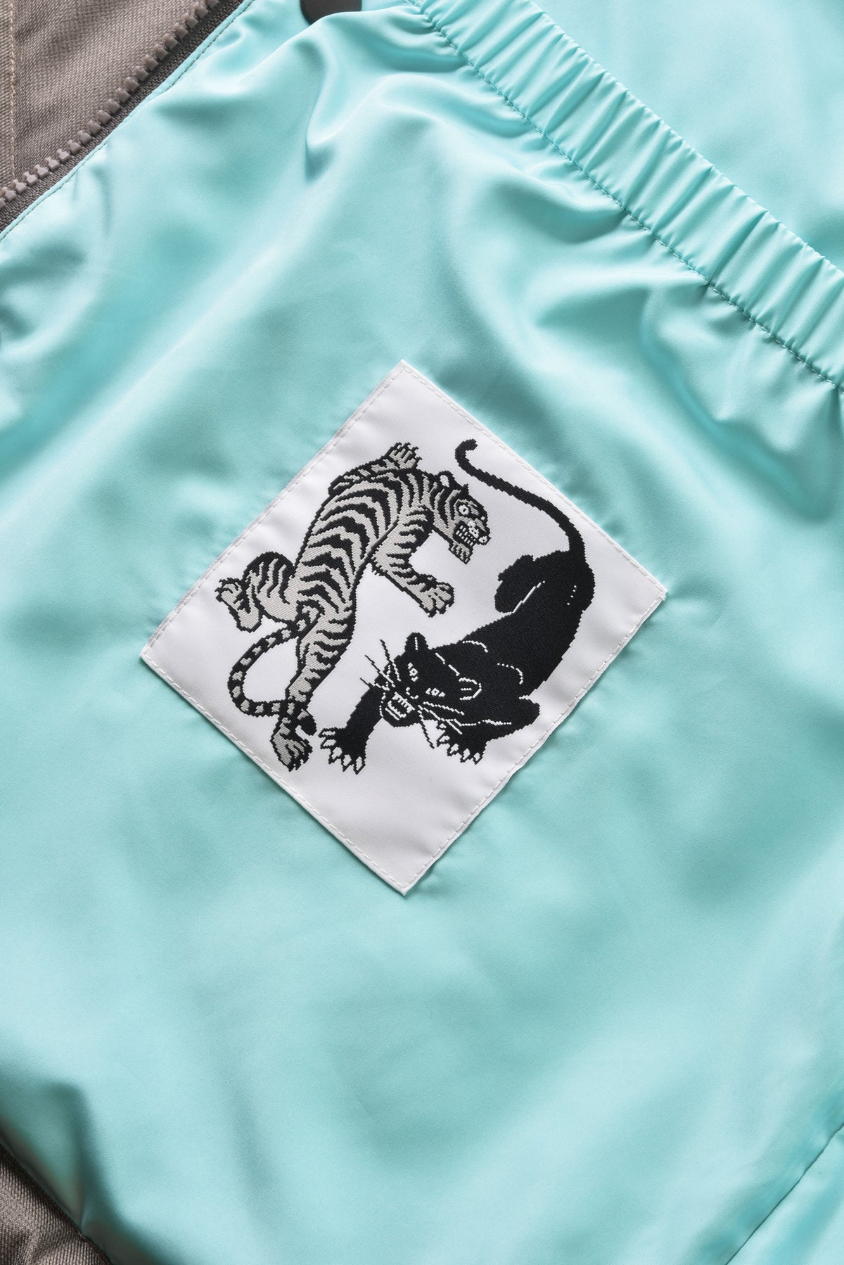 Light blue shorts with a black and white tiger patch on a white background
