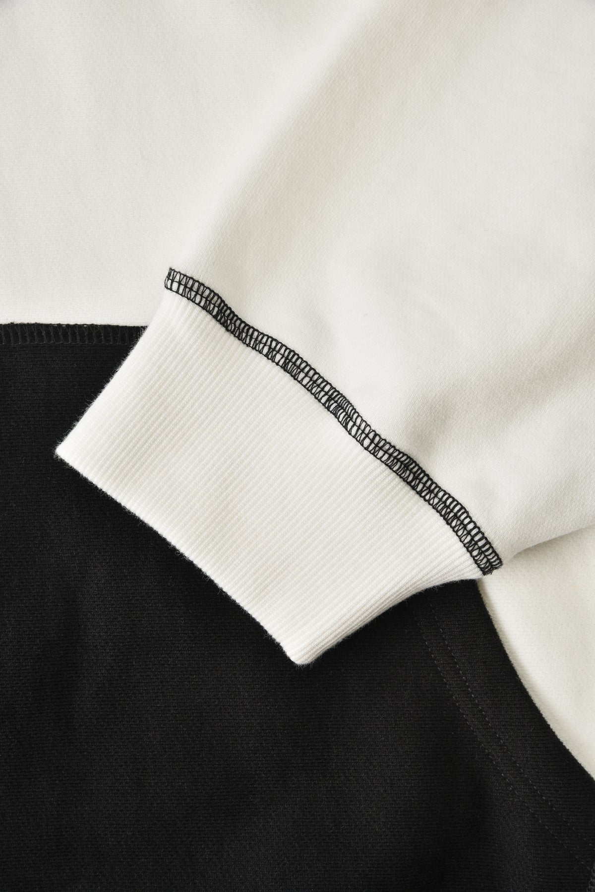 Close-up of a garment with black trim on a white background