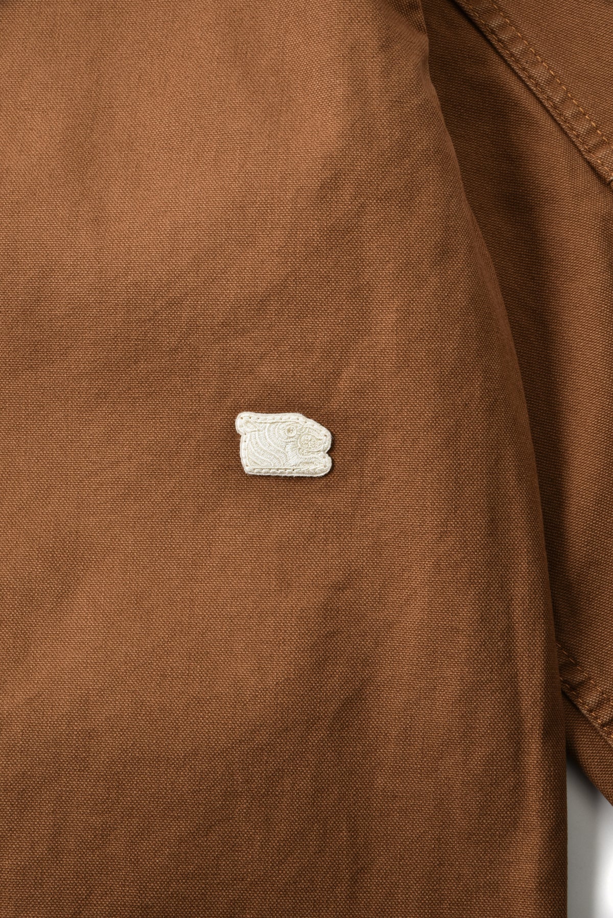 Close-up of a brown fabric surface with a small white logo.