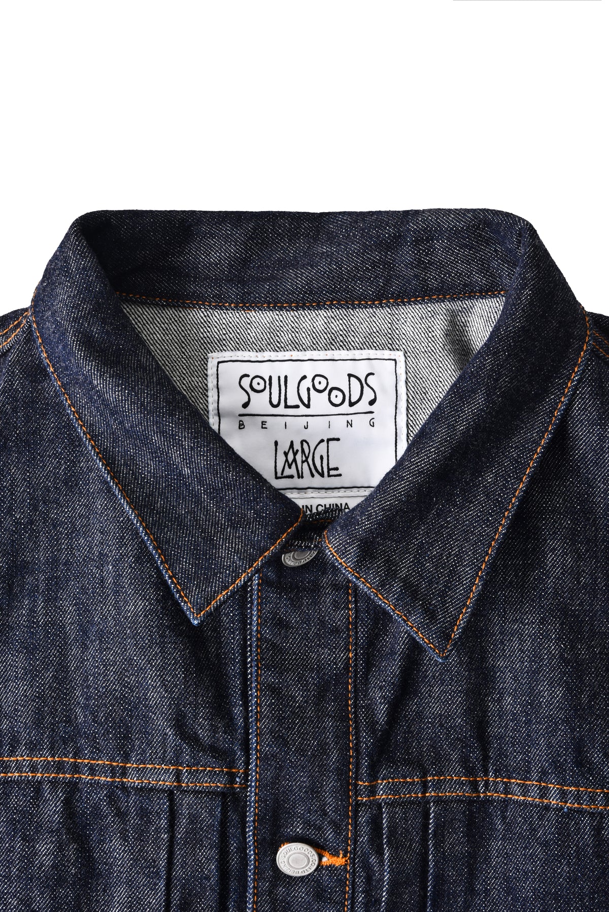 Close-up of a denim jacket collar with 'Soulgoods' label on a white background