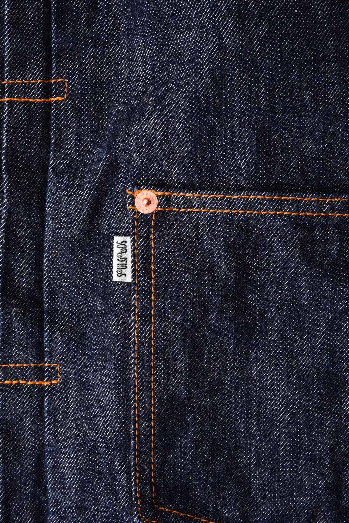 Close-up of dark denim fabric with a soulgoods brand label on a pocket.