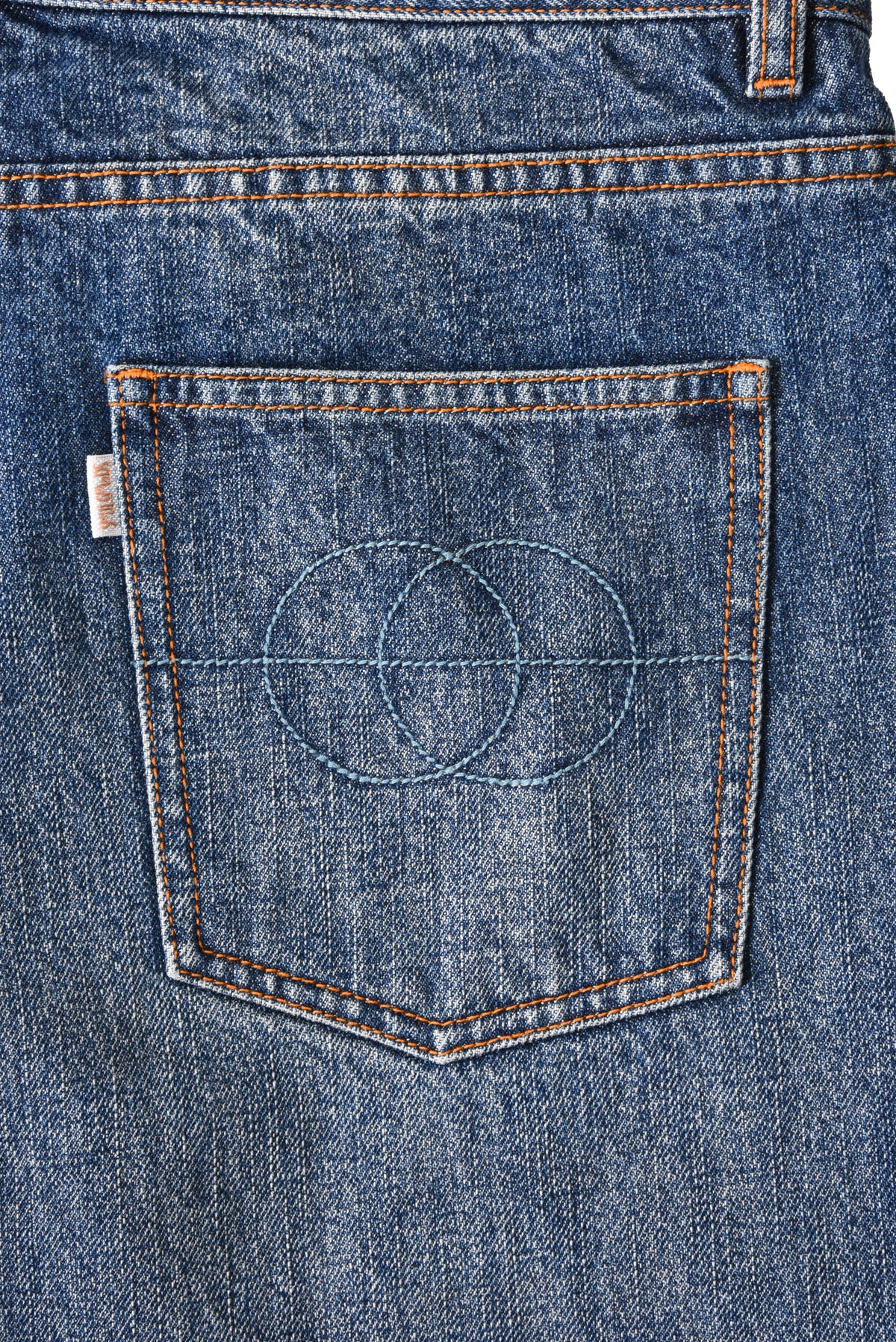 Close-up of a blue denim pocket with stitching details on a white background