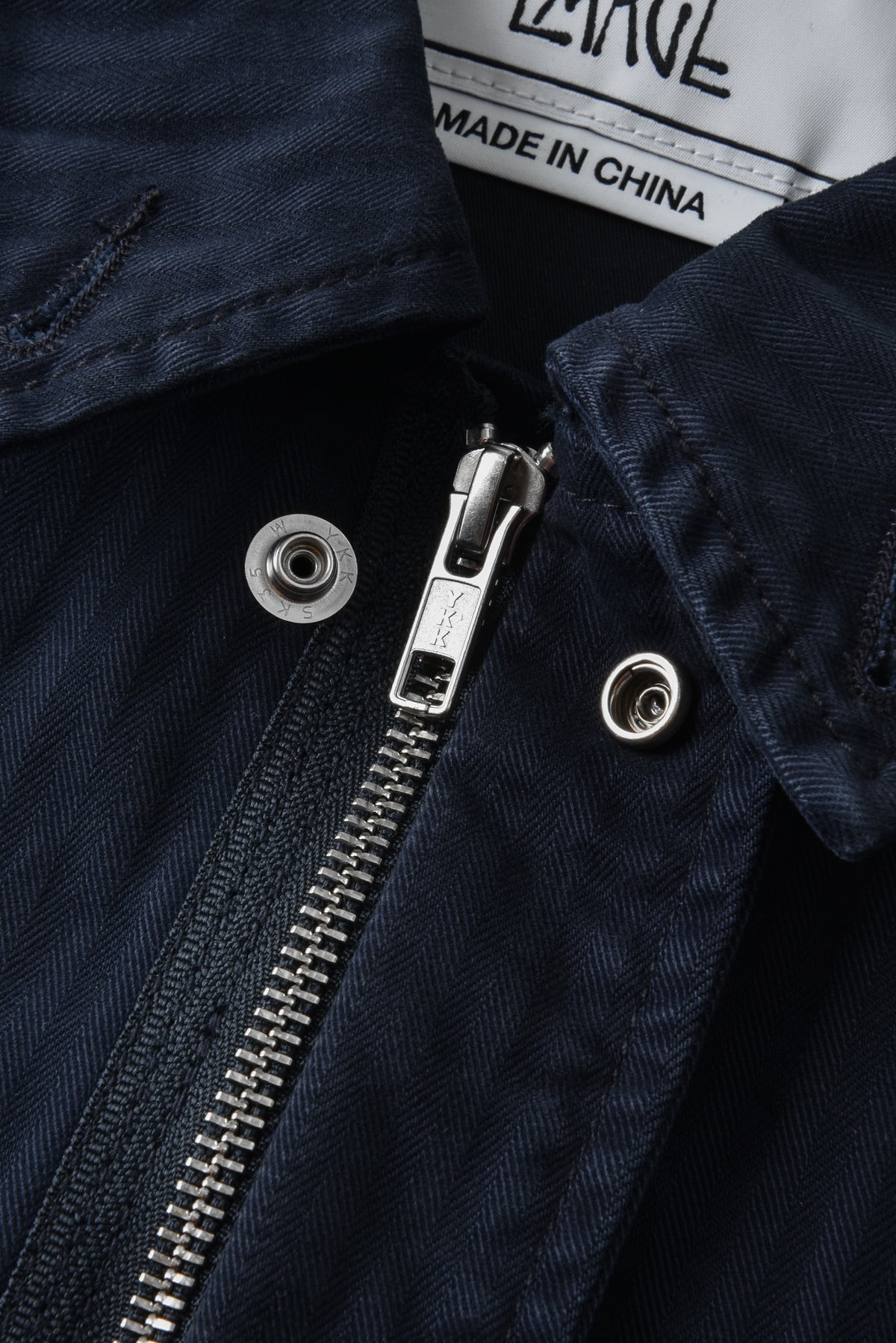 Close-up of a navy blue jacket zipper with 'Made in China' label.