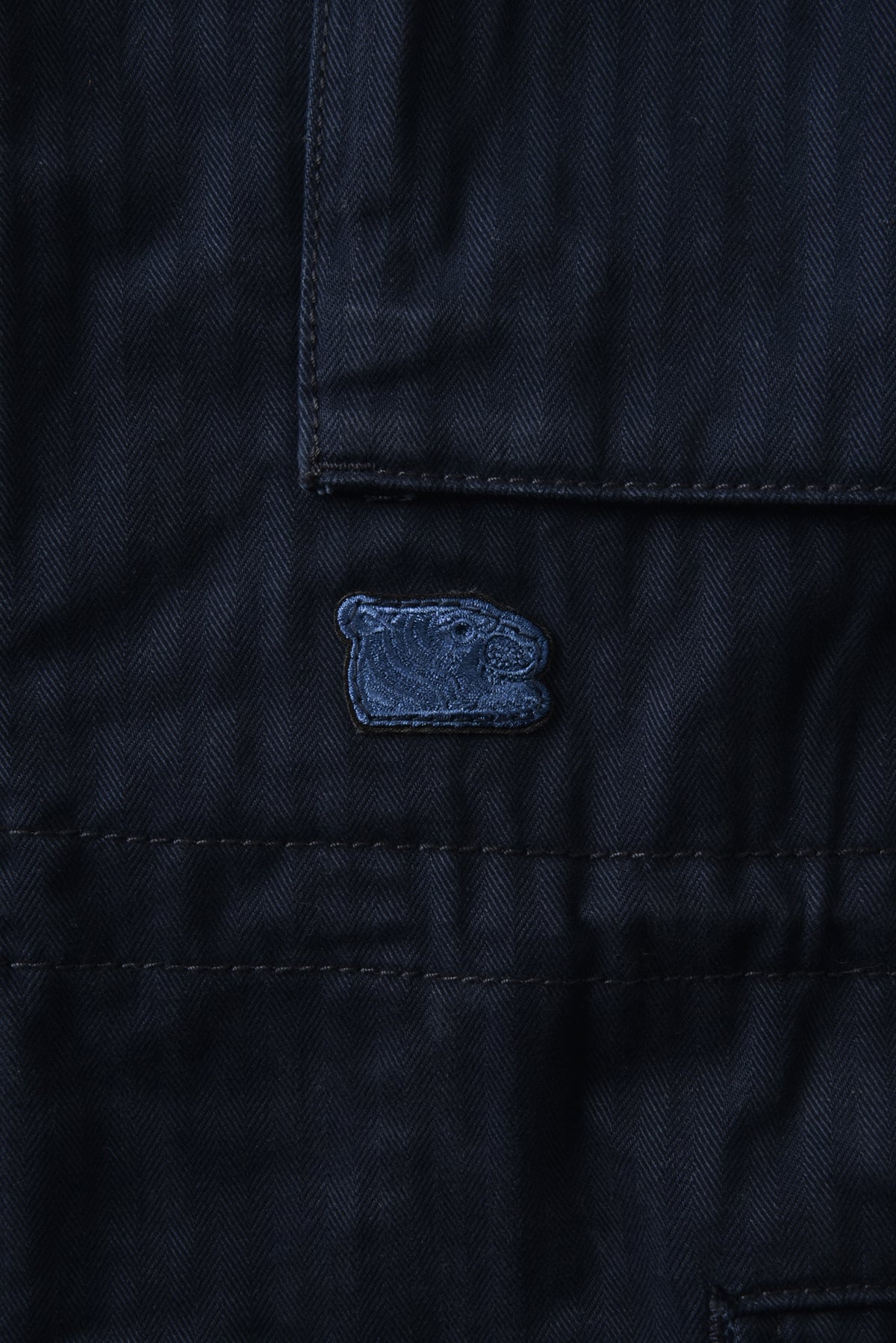 Close-up of a dark blue fabric with a soulgoods tiger head logo on a matching background