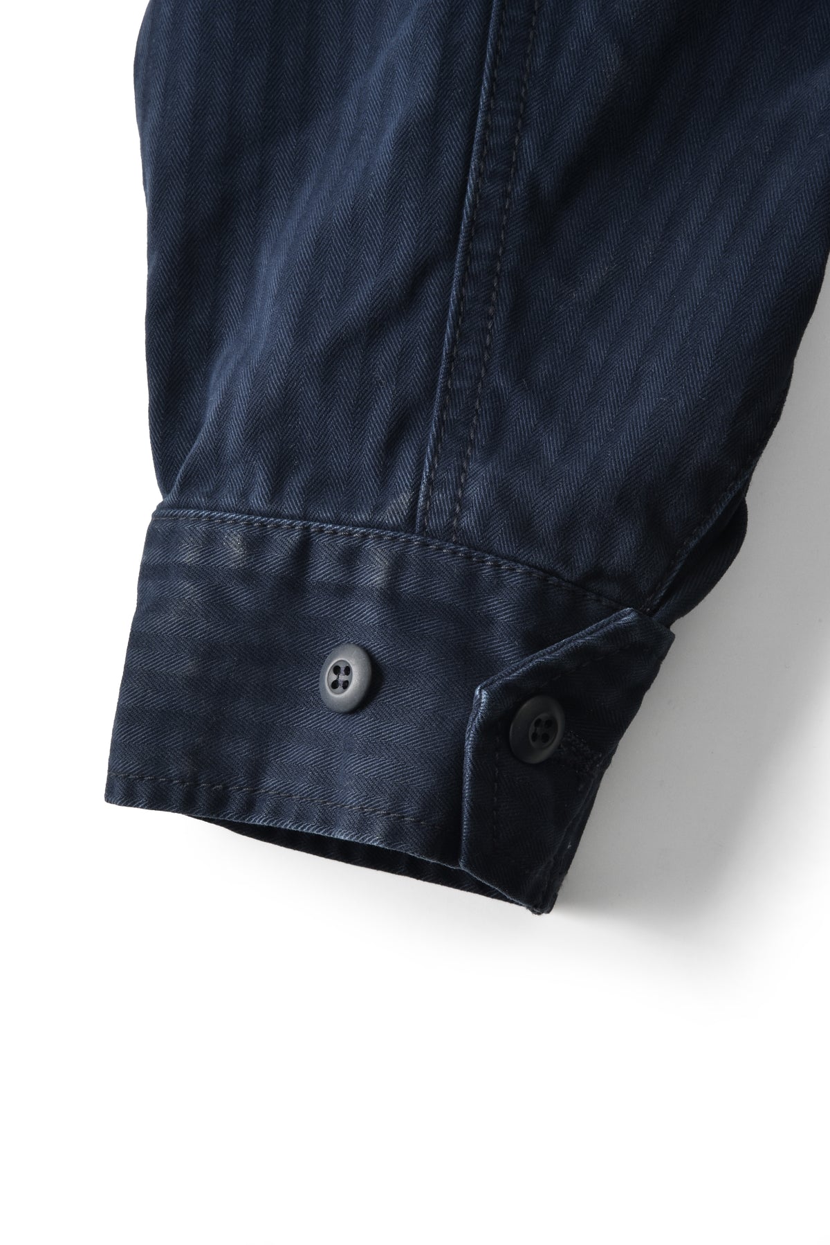 Close-up of a dark blue jacket sleeve with a button on a white background