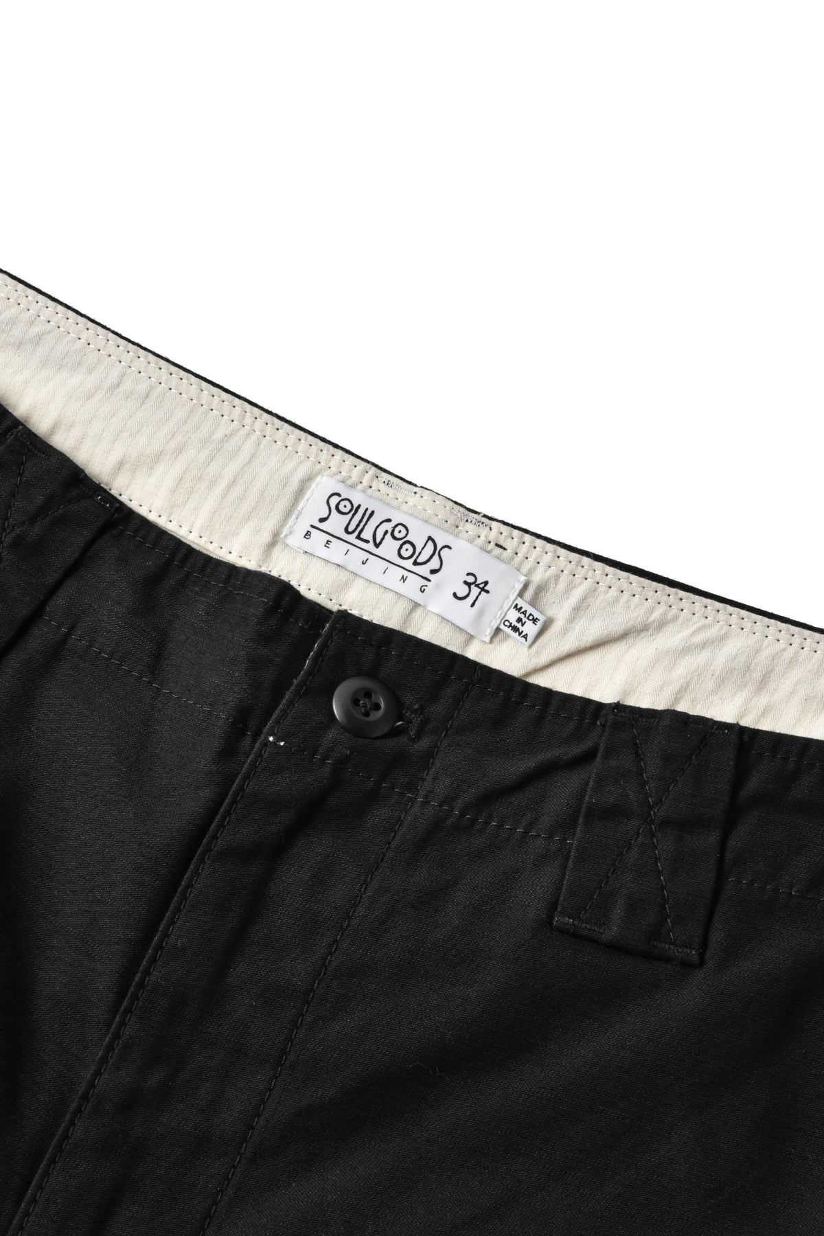 Close-up of black shorts showing the waistband, a cream-colored inner lining, and a sewn-in label that reads 'Soulgoods 34'.
