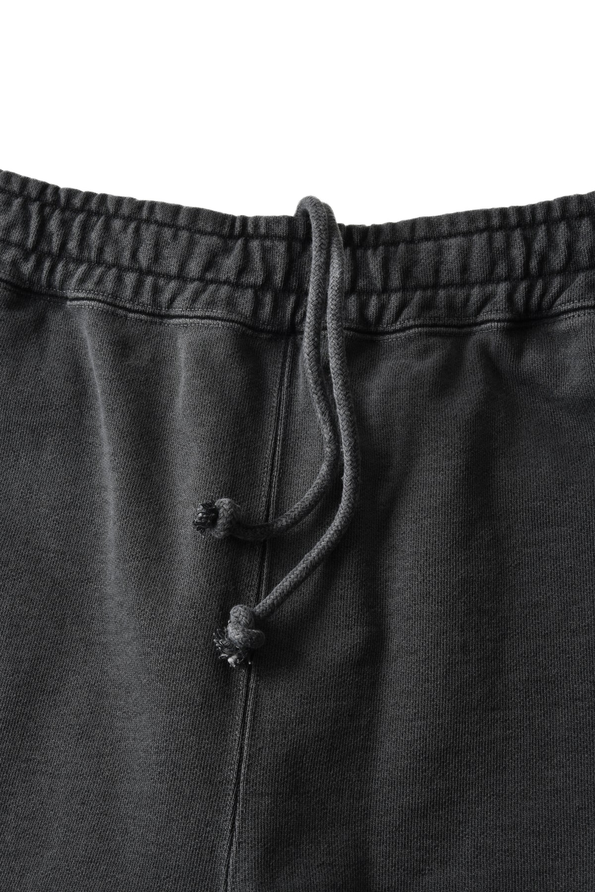 Close-up of dark charcoal gray sweatpants showing the elastic waistband and matching drawstring cords against a white background.
