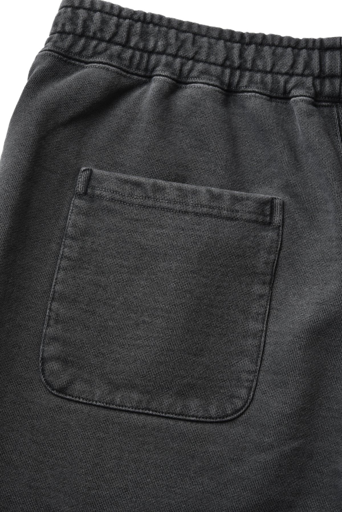 Close-up of dark charcoal gray fabric shorts showing an elastic waistband and a single front patch pocket.